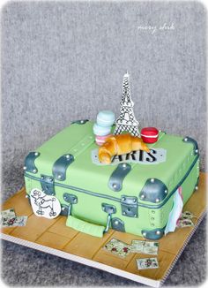 the cake is shaped like a suitcase and has an eiffel tower on top