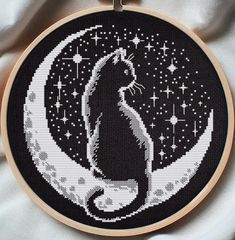 a black cat sitting on the moon with stars in it's eyes cross stitch pattern