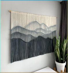 the wall hanging is decorated with black and white fringes, along with a potted plant