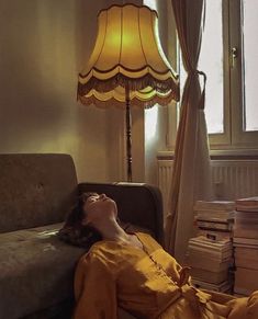 a woman laying on a couch next to a lamp