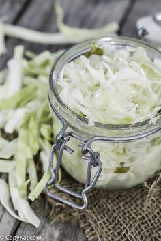 a glass jar filled with shredded cabbage on top of a wooden table