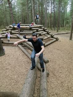 a man sitting on top of a log in the middle of a forest filled with logs