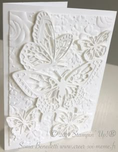 a white greeting card with an intricate butterfly design on the front and back side, sitting on top of a table