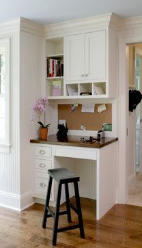 a white desk with a black stool in front of it and some books on the shelves