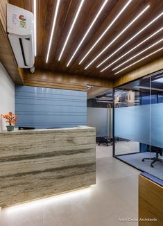 an office with wood paneling and glass walls on the front desk is lit by recessed lighting