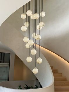 a spiral staircase with glass balls hanging from it's sides and a circular chandelier in the middle