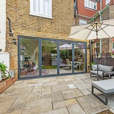 an outdoor patio with chairs and umbrellas on the side of it, next to a brick building