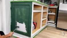 a person painting the side of a cabinet in a kitchen with green paint on it