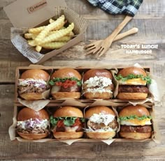 several hamburgers and french fries on a wooden table next to a box of fries