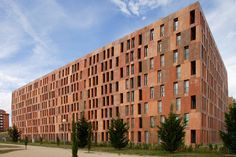 an orange brick building with lots of windows on the side and trees in front of it