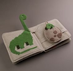 a crocheted book with a green dinosaur on the cover and a ball in the middle