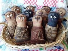 five handmade dolls in a basket with eyes and hands sticking out from their mouths