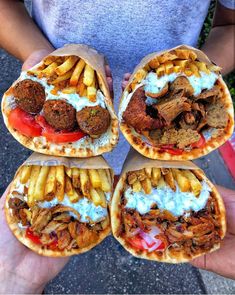 four pita sandwiches with meat, fries and sauce on them are held in the palm of someone's hand