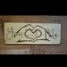 a wooden sign that says you and me with two hands making a heart in the middle