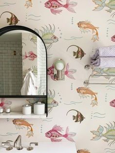 a bathroom wall with fish on it and a mirror above the sink, next to a towel rack