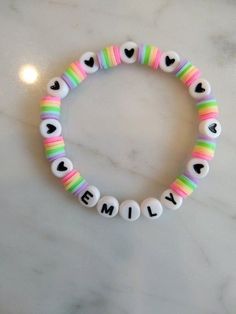 a colorful bracelet with hearts and the word family written in white beads on a marble surface