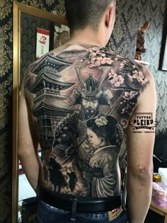 the back of a man's tattoo with an image of samurais on it