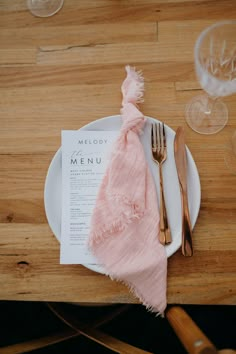 a plate with a napkin and fork on it next to wine glasses, forks and spoons