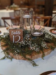 the table is set with candles and greenery for an elegant touch to the centerpiece