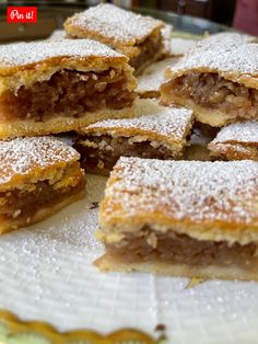 several pieces of dessert sitting on top of a white plate with powdered sugar toppings