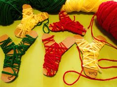 several different types of yarn and scissors on a table with some red, yellow, green, and orange string