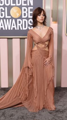 a woman in a long dress posing for the camera at an awards event with her hands on her hips