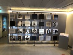 a wall with many pictures on it in an office building that is decorated with black and white photos