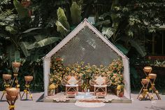 an outdoor stage set up with chairs and flowers on the ground, surrounded by candles