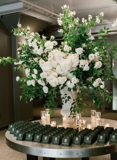 a vase filled with white flowers sitting on top of a table next to small candles