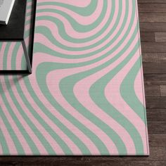 a pink and green area rug with an abstract design on the floor next to a coffee table