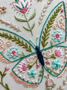 an embroidered butterfly with flowers and leaves on it's wings is seen in this close up photo