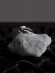 a white rock with a silver ring on it's end sitting on a black surface