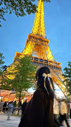 the eiffel tower is lit up at night with people walking around in front