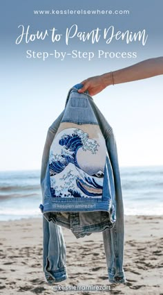 someone holding up a jean jacket with the great wave on it and text overlay that reads how to paint denim step - by - step process