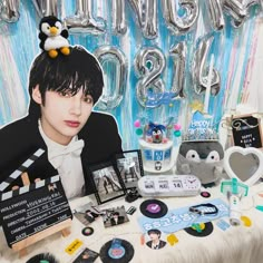 a table topped with pictures and balloons next to a penguin balloon wall that says happy birthday