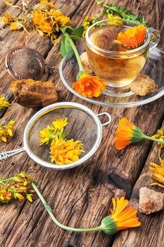 tea in a glass cup with yellow flowers next to it on a wooden table top