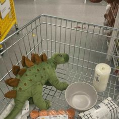 a stuffed toy dinosaur sitting in a shopping cart filled with food and milk items,