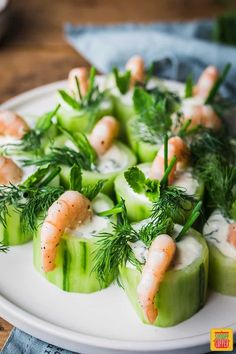 cucumbers with shrimp and dill on them are arranged on a white plate