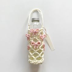 a crocheted bag with a bottle in the middle and a tag attached to it