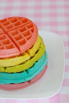 a stack of waffles sitting on top of a white plate next to a pink checkered table cloth