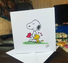 a card with a drawing of a snoopy holding a heart in it's paws