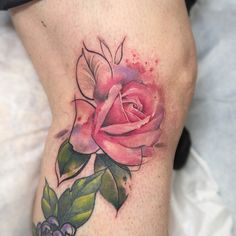 a pink rose with green leaves on the side of a woman's lower leg