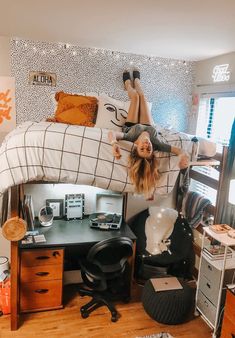 a woman laying on top of a bed next to a desk with a laptop computer