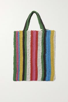 a multicolored crocheted tote bag hanging from a hook on a white wall