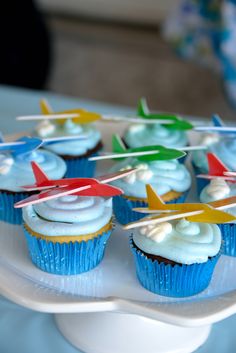 cupcakes on a plate with toothpicks in the shape of an airplane