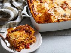 a white plate topped with lasagna next to a casserole dish