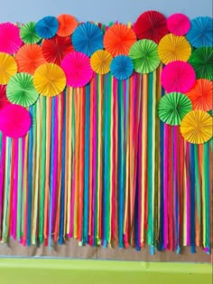 there are many colorful paper umbrellas hanging from the side of a wall with streamers attached to it