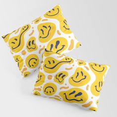 two pillows with smiley faces on them, one yellow and the other white in color