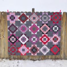 a quilt hanging on a wooden fence in the snow