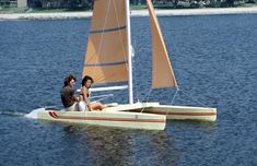 two people sitting on a small sailboat in the middle of a body of water